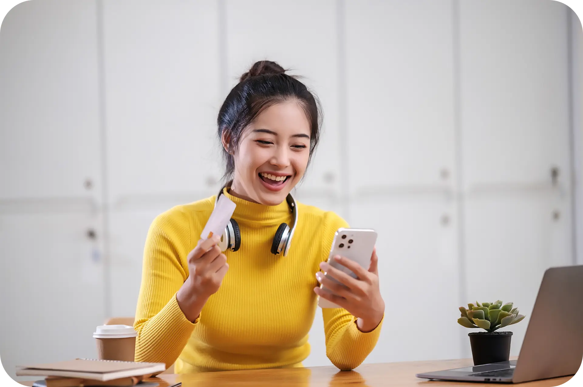 A smiling young woman holding a phone and a card.