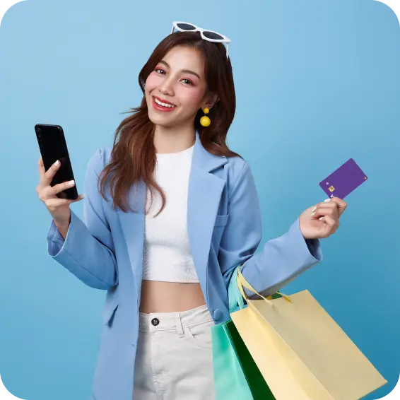 A happy young woman holding a phone in her right hand, with a U Visa Prepaid Card and shopping bags in her left.